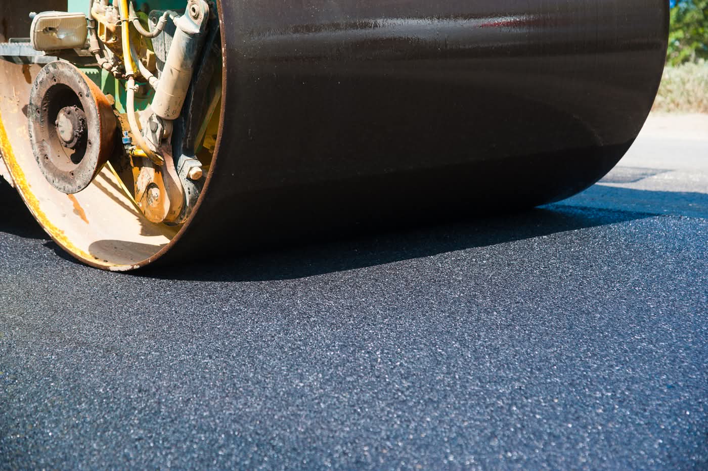 Road roller compacting fresh asphalt pavement surface