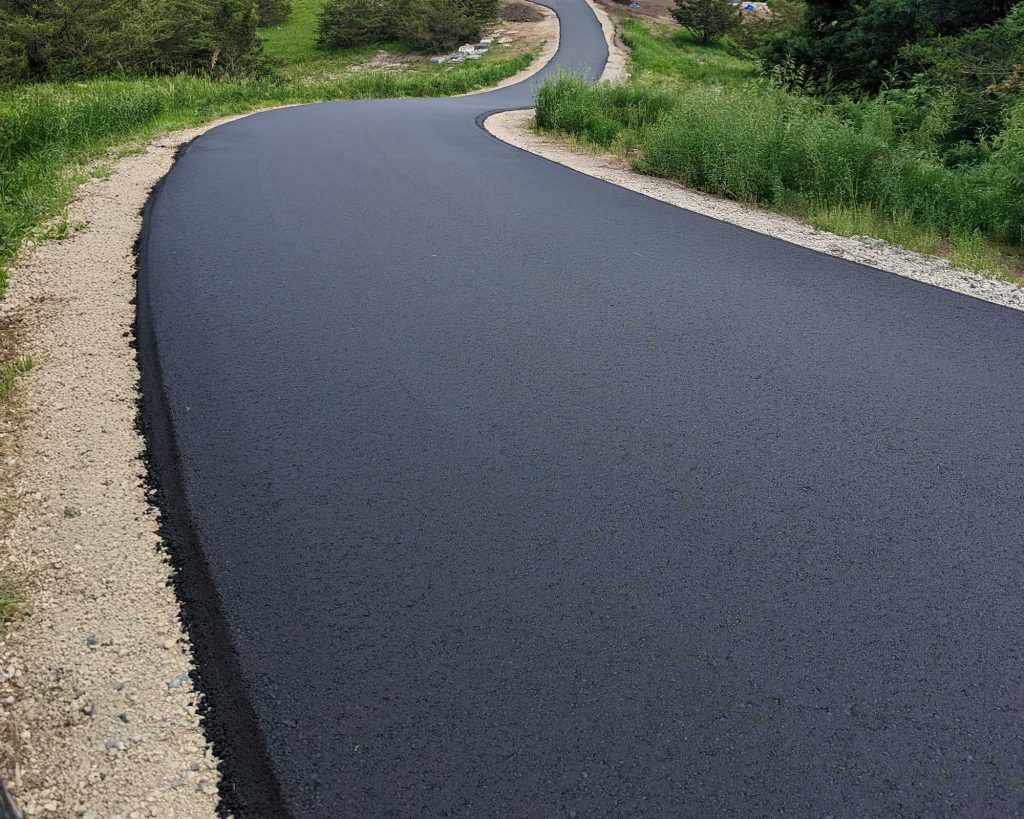 Newly paved asphalt road curving through greenery